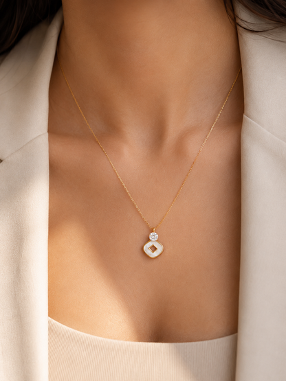 A delicate gold chain necklace with a double-hoop pendant, worn by a model. The larger lower hoop is milky white, while the smaller upper hoop is set with a clear gemstone.
